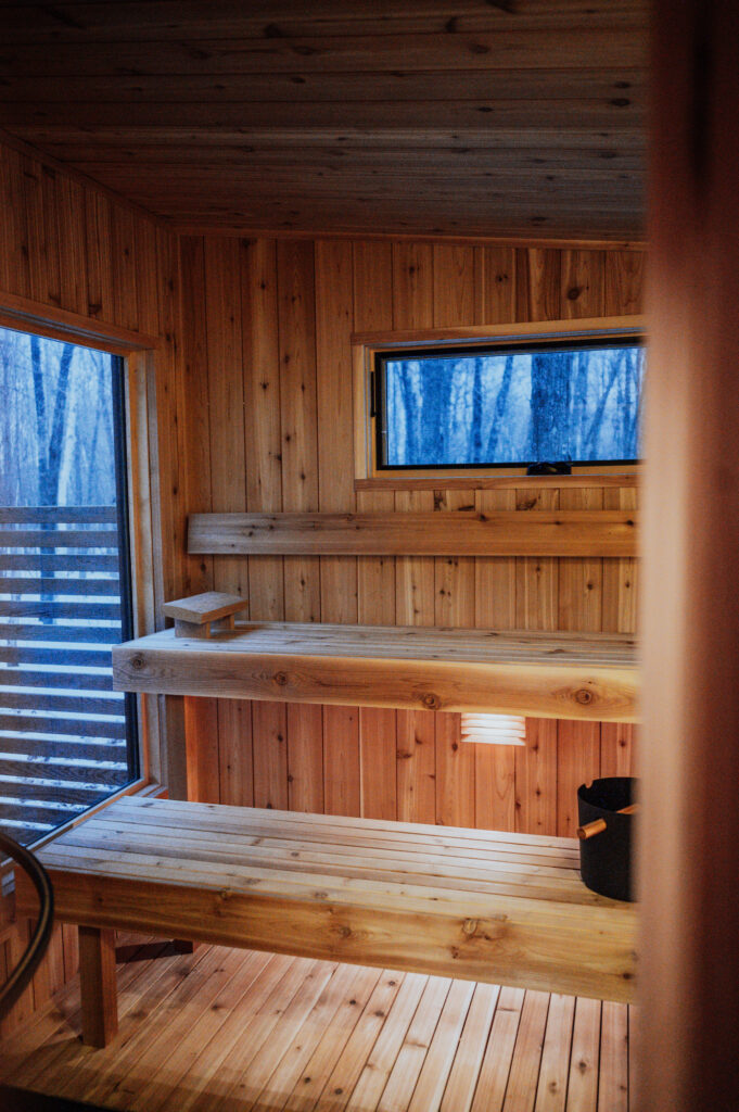 Interior view of a wood sauna with windows looking out to the woods.